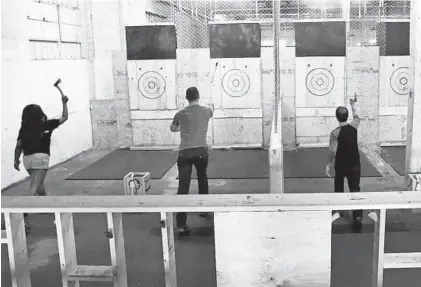  ?? KENNETH K. LAM/BALTIMORE SUN ?? Urban Axes “axeperts” throw at targets at the ax-throwing bar in Highlandto­wn.