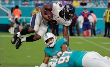 ?? Associated Press ?? Airborne: Baltimore running back Kenneth Dixon attempts to avoid Miami's Minkah Fitzpatric­k and Jordan Phillips (97) Saturday. Dixon, a Strong native, had three receptions for 18 yards in the Ravens' 27-10 victory.