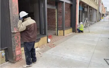  ?? (Pine Bluff Commercial/Byron Tate) ?? The Urban Renewal Agency is renovating three downtown buildings to get them ready for occupancy. Here, workers scrape paint off a building’s columns on Friday.