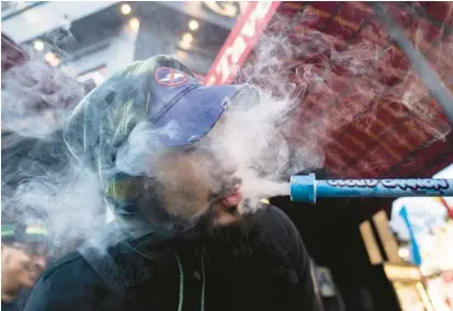  ?? JOHN MINCHILLO/AP ?? A smoker inhales from a “Cloud Cannon” on Jan. 24 outside Smacked, a pop-up cannabis dispensary in New York.