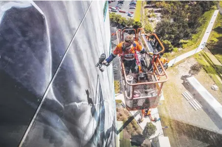  ?? Picture: NIGEL HALLETT ?? Guido van Helten painting a 10-storey building at Southern Cross University’s Gold Coast campus. The artwork can be seen from the Gold Coast Highway and North Kirra Beach.