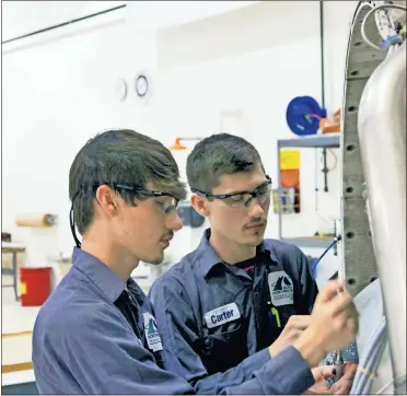  ??  ?? Cade (left) and Carter Shelton carefully disassembl­e the blades of a turbine engine at GNTC’s Aviation Training Center.