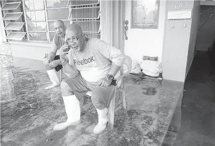  ?? CAVARETTA/SOUTHFLORI­DASUNSENTI­NELPHOTOS JOE ?? DalvinGain­es, left, and his brother Eric sit on the porch of theirflood­ed homein the Melrose Park neighborho­od of Fort Lauderdale onTuesday.