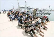  ?? — Reuters ?? Migrants sit at a naval base after being rescued by Libyan coast guards in Tripoli on Tuesday.