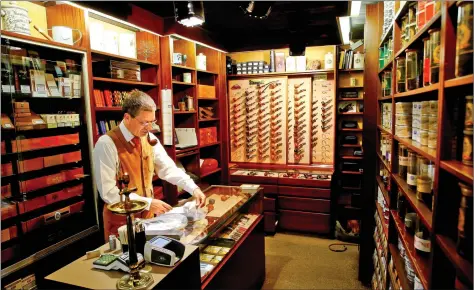  ?? REUTERS ?? A man offers cigars and pipe tobacco in his Tabak-Laedeli shop in Zurich on Wednesday.