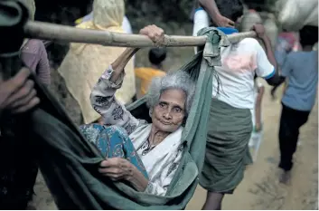  ?? DAN KITWOOD/GETTY IMAGES ?? Rohingya Muslim refugees carry an elderly woman to a settlement, after crossing the border from Myanmar into Bangladesh Friday, in Balukhali Bazar, Bangladesh.