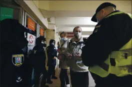  ?? EFRAM LUKATSKY — THE ASSOCIATED PRESS ?? Policemen check the passenger passes at a subway station entrance in Kyiv, Ukraine, on Monday. Authoritie­s in Kyiv recently introduced tighter virus lockdown restrictio­ns.