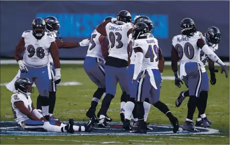  ?? WADE PAYNE — THE ASSOCIATED PRESS ?? Baltimore Ravens players sit and stand on the Tennessee Titans’ logo at the 50-yard line after Ravens cornerback Marcus Peters intercepte­d a pass against the Titans late in the fourth quarter of an NFL wild-card playoff game Sunday in Nashville, Tenn.