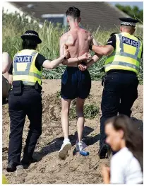  ??  ?? Held: Police escort a youth off the beach