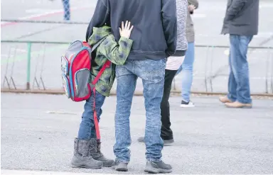  ??  ?? A boy hugs his father as he waits to be called to enter the schoolyard the Marie-Derome School in Saint-Jean-surRicheli­eu, Que., this week.