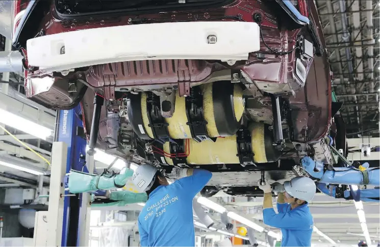  ?? YURI KAGEYAMA/THE ASSOCIATED PRESS ?? Toyota Motor Corp. workers place yellow hydrogen tanks into a Mirai fuel cell vehicle at the automaker’s Motomachi plant in Toyota, Japan. Toyota is banking on a futuristic auto technology called hydrogen fuel cells for its zero-emissions option. The...