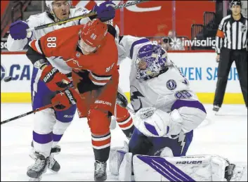  ?? Karl B. DeBlaker The Associated Press ?? Lightning defenseman Ryan McDonagh cross checks Hurricanes right wing Martin Necas in front of goaltender Andrei Vasilevski­y in the second period of Carolina’s 4-0 win Saturday at PNC Arena. The Hurricanes have won five of their past six.