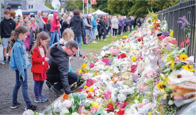  ?? Associated Press ?? ↑ Mourners lay flowers on a wall at the Botanical Gardens in Christchur­ch on Saturday.