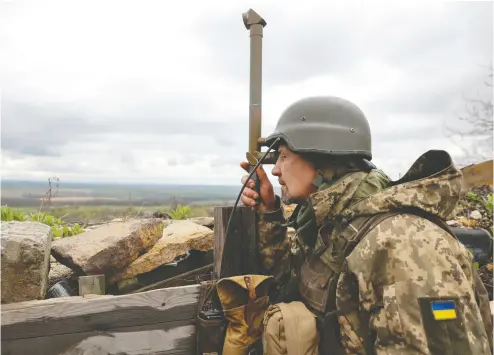  ?? SERHII NUZHNENKO / REUTERS ?? A Ukrainian service member uses a periscope in Donetsk Region on Friday as Russia’s attack on Ukraine continues.