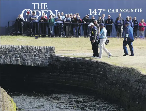  ?? ALASTAIR GRANT/THE ASSOCIATED PRESS ?? Kevin Kisner talks to officials after hitting the ball into the Barry Burn on the 18th hole during second-round play at the British Open in Carnoustie, Scotland on Friday. Despite finishing with a double bogey, the American shares the lead at the midway point.