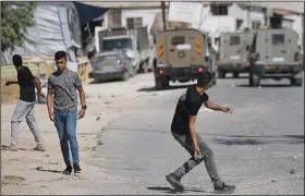  ?? (File Photo/AP/Majdi Mohammed) ?? Palestinia­ns throw stones at an Israeli military vehicle July 24 following a military raid of the Askar refugee camp in the West Bank city of Nablus.