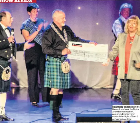  ??  ?? Sparkling success Sandra Brown, founder of the Moira Anderson Foundation, accepts a donation from some of the Night of Stars 5 performers on stage