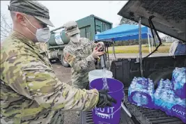  ?? Rogelio V. Solis The Associated Press ?? Mississipp­i Army National Guard Sgt. Chase Toussaint, right, and Staff Sgt. Matthew Riley fill drums Monday in Jackson, Miss., with water for flushing toilets.