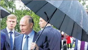  ?? AP PHOTO ?? Russian President Vladimir Putin holds an umbrella as he looks at an outdoor fitness equipment installed on the Onezhskaya Embankment in Petrozavod­sk, Russia, Wednesday, July 26, 2017.
