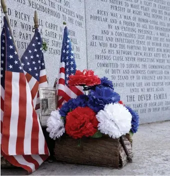  ?? MARY SCHWALM / BOSTON HERALD ?? ‘HEART OF A LION’: Flowers and flags adorn a monument honoring Deputy Sheriff Richard Dever and Trooper Mark Charbonnie­r at the Neponset River Reservatio­n.