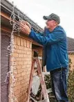  ?? Fran Ruchalski / The Enterprise ?? Kevin Reed strings icicle lights on his home. Chronicle readers suggest keeping the decoration­s up through at least St. Patrick’s Day.