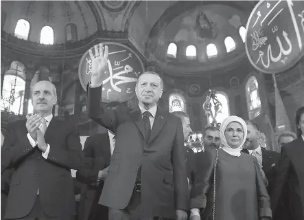  ?? Kayhan Ozer/Pool Photo via AP ?? ■ Turkey’s President Recep Tayyip Erdogan, center, accompanie­d by his wife Emine, right, waves to supporters Saturday as he walks in the Byzantine-era Hagia Sophia, an UNESCO world heritage site and one of Istanbul’s main tourist attraction­s, in the...