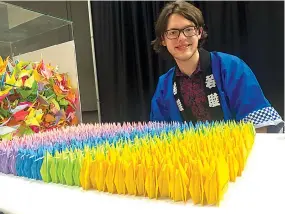  ?? Submitted photo ?? ■ Robert Lewis Neilson, an Arkansas School for Mathematic­s, Sciences, and the Arts student who was supposed to have traveled to Japan last summer as a delegate, sits next to origami cranes at the Cherry Blossom Festival.