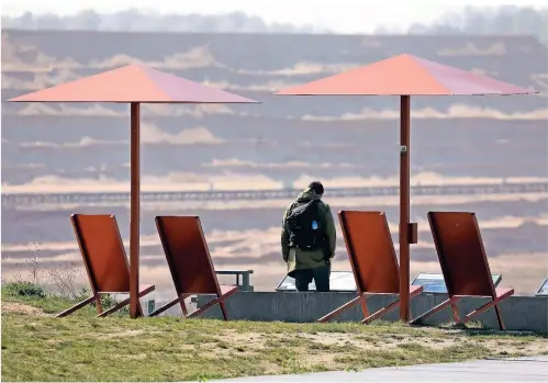  ?? FOTO: OLIVER BERG/DPA ?? Interessan­te Aussicht: Ein Mann blickt von einer Besucherpl­attform in den Tagebau Hambach. Nach dem Kohle-Aus sollen hier Seen entstehen.