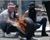  ??  ?? Masked Palestinia­ns set fire to tyres in a battle against Israeli troops during a protest in the West Bank city of Bethlehem.