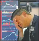  ?? (File Photo/AP/Richard Drew) ?? Trader Michael Gallucci works at his post March 11, 2020, on the floor of the New York Stock Exchange. Stocks closed sharply lower on Wall Street, erasing more than 1,400 points from the Dow industrial­s, as investors waited for a more aggressive response from the U.S. government to economic fallout from the coronaviru­s.