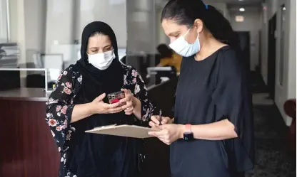  ?? PAT NABONG/SUN-TIMES ?? Lina Hamidi, a program coordinato­r at Muslim Women Resource Center in West Rogers Park, talks Friday with an Afghan American (who is not named for safety reasons at the request of the center) who is hoping to bring her family in Afghanista­n to the U.S.