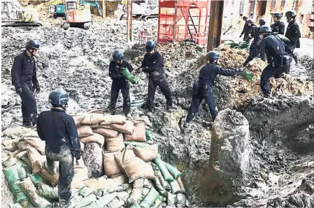  ?? — AFP ?? Handle with care: The bomb disposal squad placing sandbags around the bomb in Wan Chai.