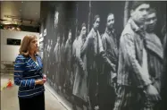  ?? TONY GUTIERREZ — THE ASSOCIATED PRESS ?? Dallas Holocaust and Human Rights Museum President and CEO, Mary Pat Higgins, pauses as she gives a tour of the museum in Dallas, to look at a wall size image of Jews marching. When Dallas’ Holocaust museum reopens in a few weeks it will not only be in a new building five times the size of its previous location, but will take visitors on a journey that also includes modern-day genocides and the evolution of human and civil rights in the U.S.