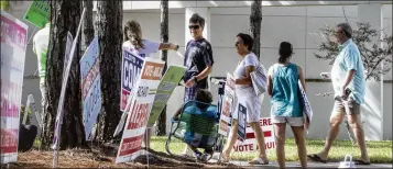  ?? DAMON HIGGINS / THE PALM BEACH POST ?? People make their way past political supporters and politician­s to cast their votes Sunday morning as the Supervisor of Elections Office opens its doors on the last day of early voting.