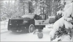  ?? California Highway Patrol Truckee office ?? A highway patrol vehicle is stopped in the snow next to an umbrella and lawn chair near the Donner Summit rest area on Monday in Donner Pass. A rare winter-like storm brought more snow to the Sierra Nevada on Monday, giving skiers the opportunit­y to...