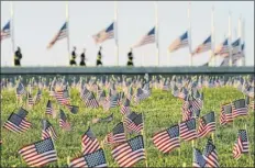  ?? J. Scott Applewhite / Associated Press ?? Activists from the COVID Memorial Project mark the deaths of 200,000 lives lost in the U.S. to COVID-19 after placing thousands of small American flags on the grounds of the National Mall in Washington on Tuesday.