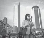  ?? GETTY IMAGES ?? A woman wears a mask while using an iPhone in Wuhan, China, source of the coronaviru­s.