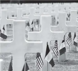  ?? SEAN GALLUP Getty Images ?? U.S. and French flags stand Wednesday at the graves of U.S. soldiers near Colleville-Sur-Mer, France. The Normandy American Cemetery contains the graves of more than 9,600 U.S. soldiers killed on D-Day and in the Battle of Normandy.