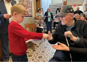  ?? (Special to The Commercial/University of Arkansas System Division of Agricultur­e) ?? Liam Pruett (left) hands a Veterans Day program to veteran Joe Rawls on Nov. 11 at the Cleveland County Courthouse.