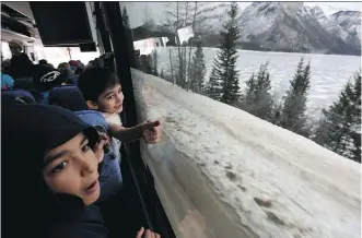  ?? LEAH HENNEL ?? Syrian refugees Khaled Hussain, 6, left, and Abdo Alotaiki, 13, react to seeing the mountains and Lake Minnewanka in Banff National Park during a tour of the Rockies offered by Brewster Travel Canada.