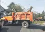  ??  ?? Cleanup crews use grapplers and dump trucks to load up and carry away debris from last week’s storm.