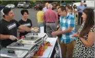  ?? RICHARD PAYERCHIN — THE MORNING JOURNAL ?? From left, Jenso Soto, co-owner of Smash - The World’s Greatest Food Truck of Lorain, hands over a sample of pumpkin basil macaroni and cheese, a dish prepared with Smash co-owner Verita Soto, his sister.