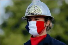  ?? Christophe Ena/Associated Press ?? A firefighte­r wears a face mask with the colors of the French flag on Tuesday before the Bastille Day parade on the Champs-Elysees Avenue in Paris.