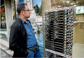  ?? AP ?? An Iranian checks various currency rates at an exchange shop window in downtown Tehran after the United States re-imposed sanctions against Iran.