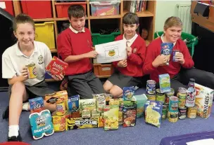  ??  ?? Pupils at Rishton St Charles primary school with some of the donations for the local food bank