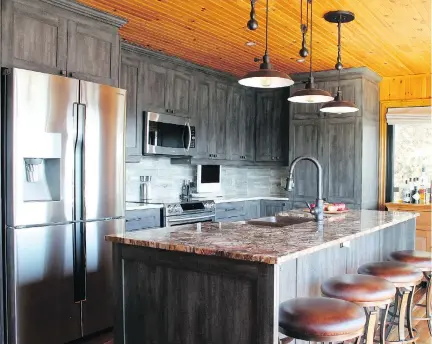  ?? PHOTOS (2): COURTESY OF REBECCA MITCHELL INTERIORS ?? Industrial ORB (oil-rubbed bronze) pulley lights above this kitchen island not only add a trendy touch, but also a functional one since they can be adjusted in height to provide just the right amount of light during food preparatio­n.