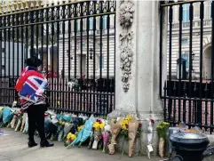 ?? (Kate Ng) ?? A mourner dressed in a Union Jack flag lays flowers in front of Buckingham Palace in tribute to the Duke of Edinburgh