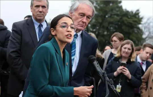  ?? Alex Wong/Getty Images ?? U.S. Rep. Alexandria Ocasio-Cortez, D-N.Y., speaks as Sen. Ed Markey, D-Mass., listens during a news conference to unveil the Green New Deal on Thursday in front of the U.S. Capitol.