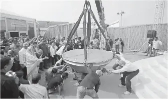  ??  ?? Officials help place a giant pan containing “khichdi” on a weighing machine in an attempt to enter the Guinness World Record for the “largest servings of rice and beans,” at the World Food India exhibition in New Delhi on Saturday.