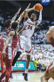  ?? AP PHOTO/VASHA HUNT ?? Alabama forward Brandon Miller (24) fires off a shot Saturday with Arkansas guard Nick Smith Jr. (3) and guard Davonte Davis (4) defending during the second half of an NCAA college basketball game in Tuscaloosa, Ala.